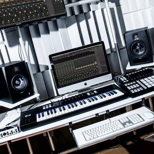 Estúdio de produção com monitores, teclado MIDI e tela mostrando sessão de mixagem