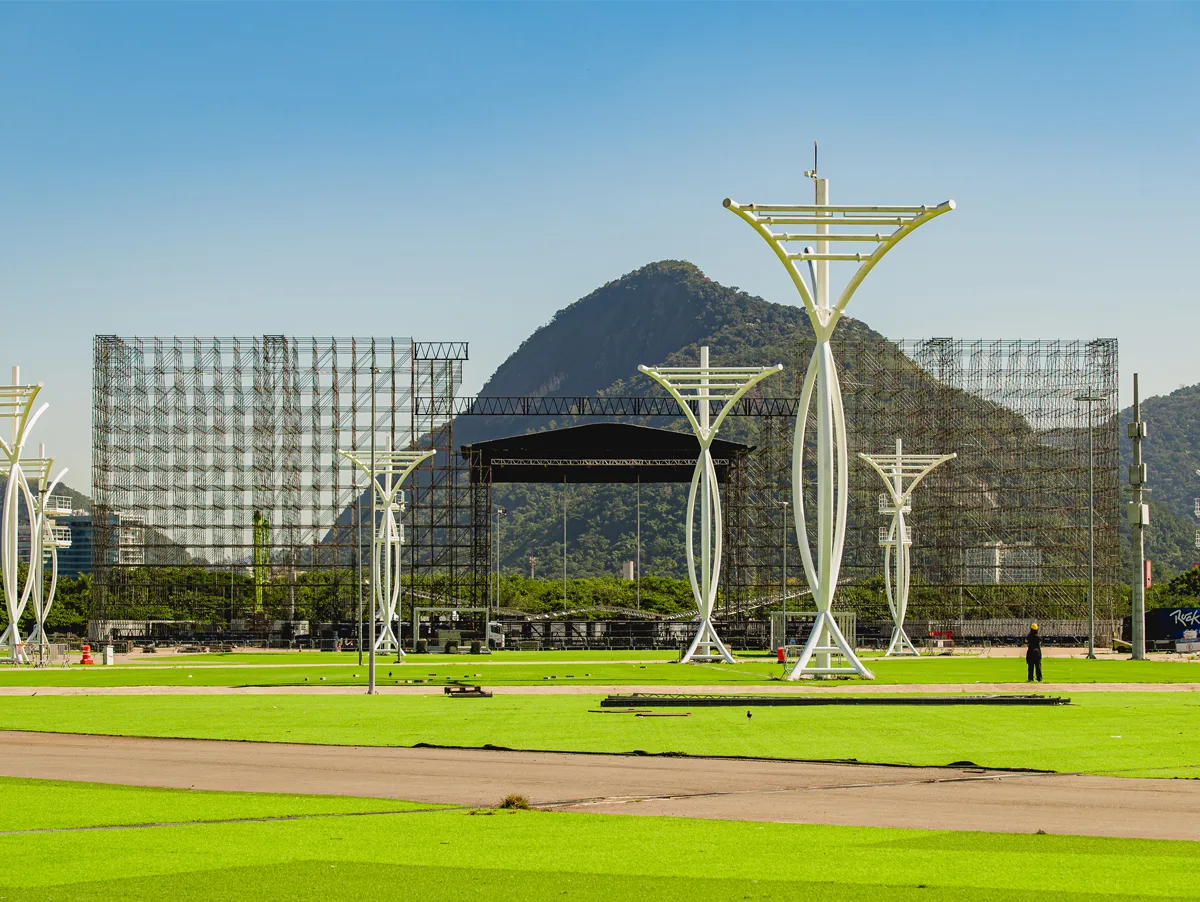 Montagem da Cidade do Rock para o Rock in Rio 2026, com as estruturas de palco erguidas e a Pedra da Gávea ao fundo